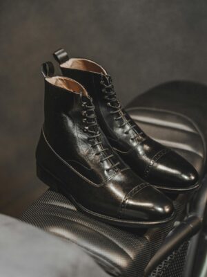 Close-up of stylish black leather boots on an elegant textured surface, highlighting high fashion and craftsmanship.