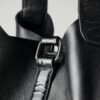 Detailed view of a black leather bag showing strap and buckle design.