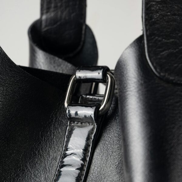 Detailed view of a black leather bag showing strap and buckle design.